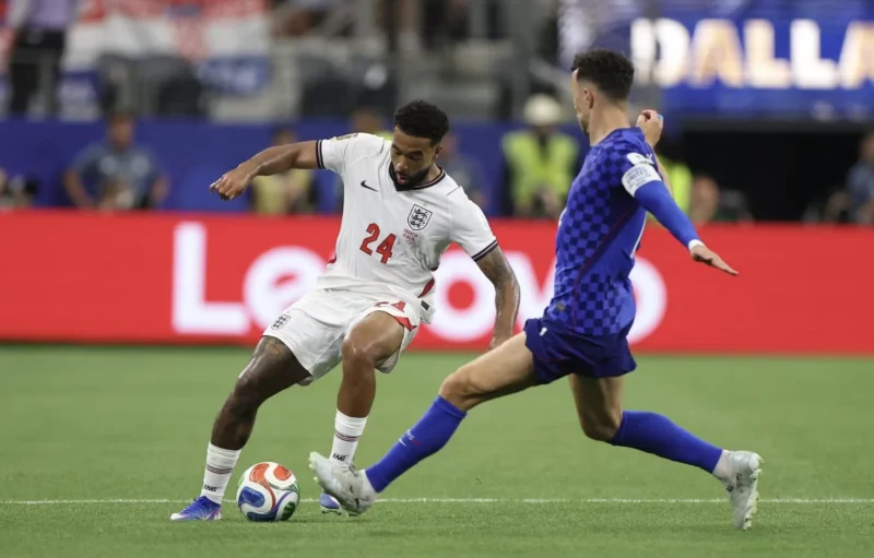 An England Player Dribbles Under Pressure from a Croatia Player